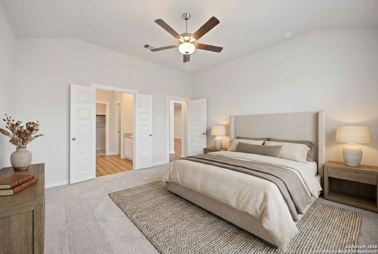 16447 Ginger Crossing Elmendorf, TX 78112 - Photo 4 of 6 a bedroom with a large bed and a chandelier