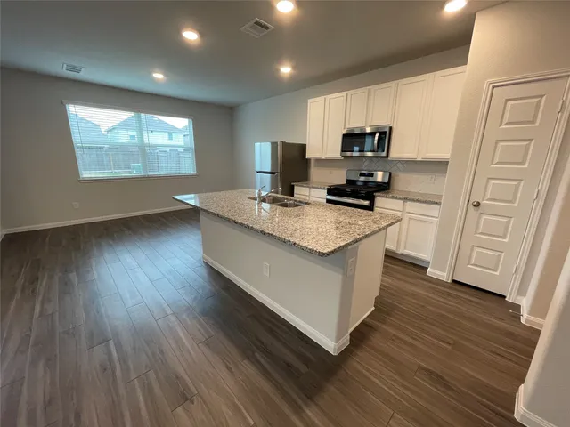 a kitchen with granite countertop a refrigerator microwave and sink