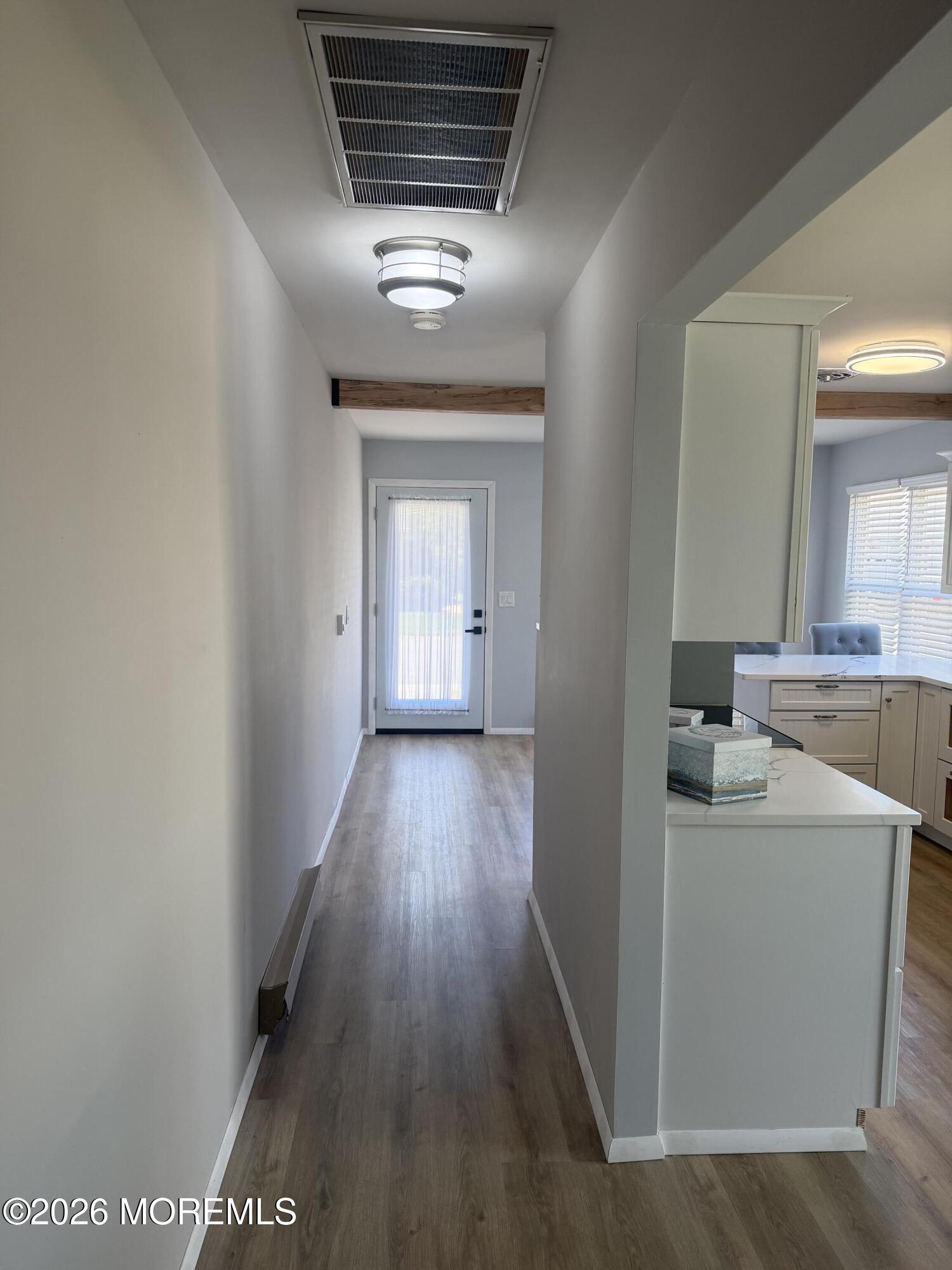 31 Homestead Drive, Unit A Whiting, NJ 08759 - Photo 17 of 23 a view of a hallway to an empty room with wooden floor and a kitchen