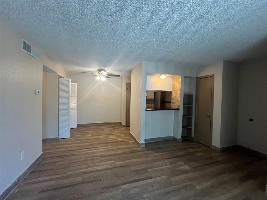 1516 Bay Area Boulevard, Unit 14 Houston, TX 77058 - Photo 9 of 19 a view of an empty room with wooden floor and a kitchen