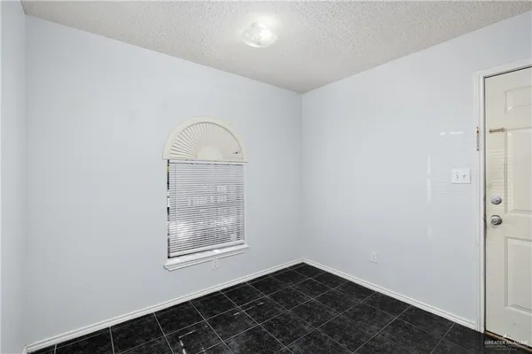a view of an empty room with closet and a window