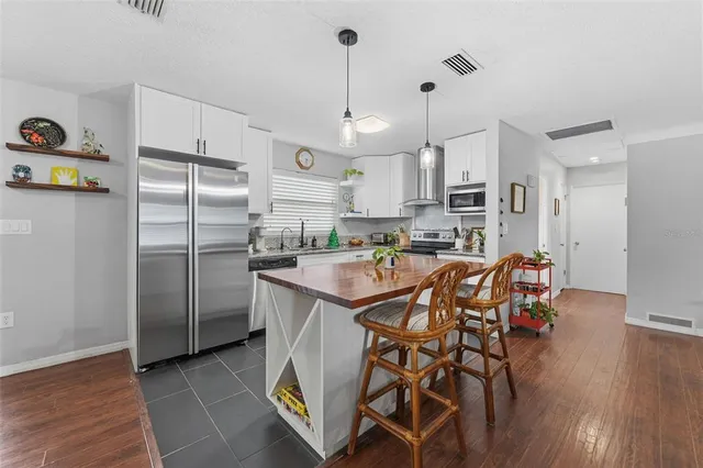 a kitchen with stainless steel appliances granite countertop a dining table chairs refrigerator and microwave