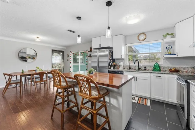a kitchen with stainless steel appliances granite countertop table chairs and wooden floors