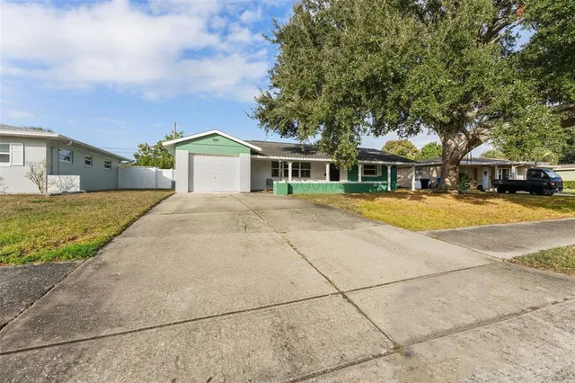a view of a white house with a swimming pool and lawn chairs under an umbrella