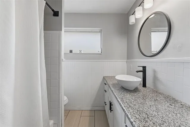 a bathroom with a granite countertop toilet a sink and a mirror