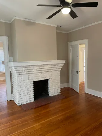 an empty room with wooden floor cabinet and windows