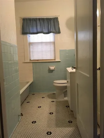 an empty room with wooden floor a ceiling fan a fireplace and windows