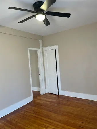 an empty room with wooden floor a ceiling fan and fireplace