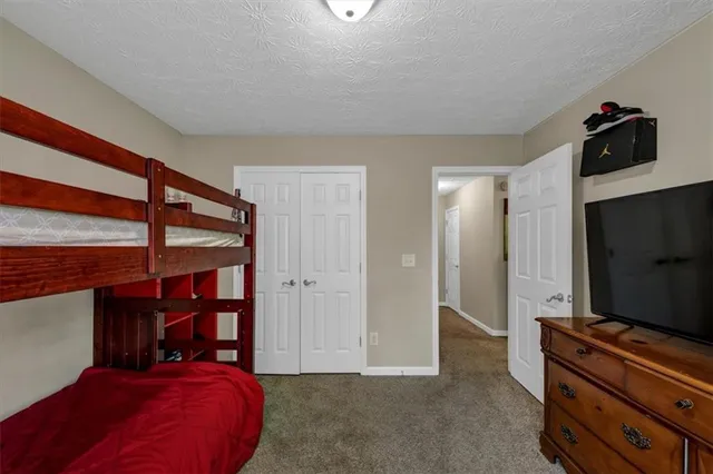 a bedroom with a bed and a flat tv screen on the dresser