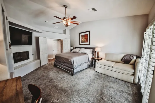 a spacious bedroom with a bed a couch and a flat screen tv