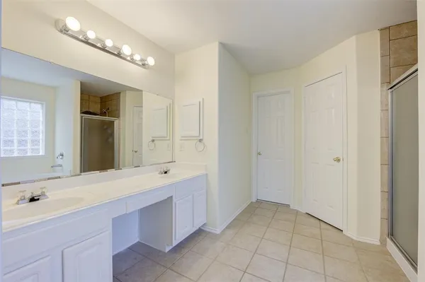 a spacious bathroom with a double vanity sink a mirror and a shower