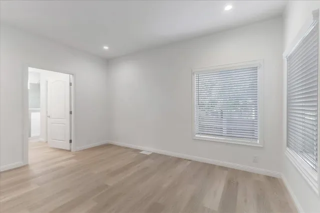 an empty room with wooden floor and windows