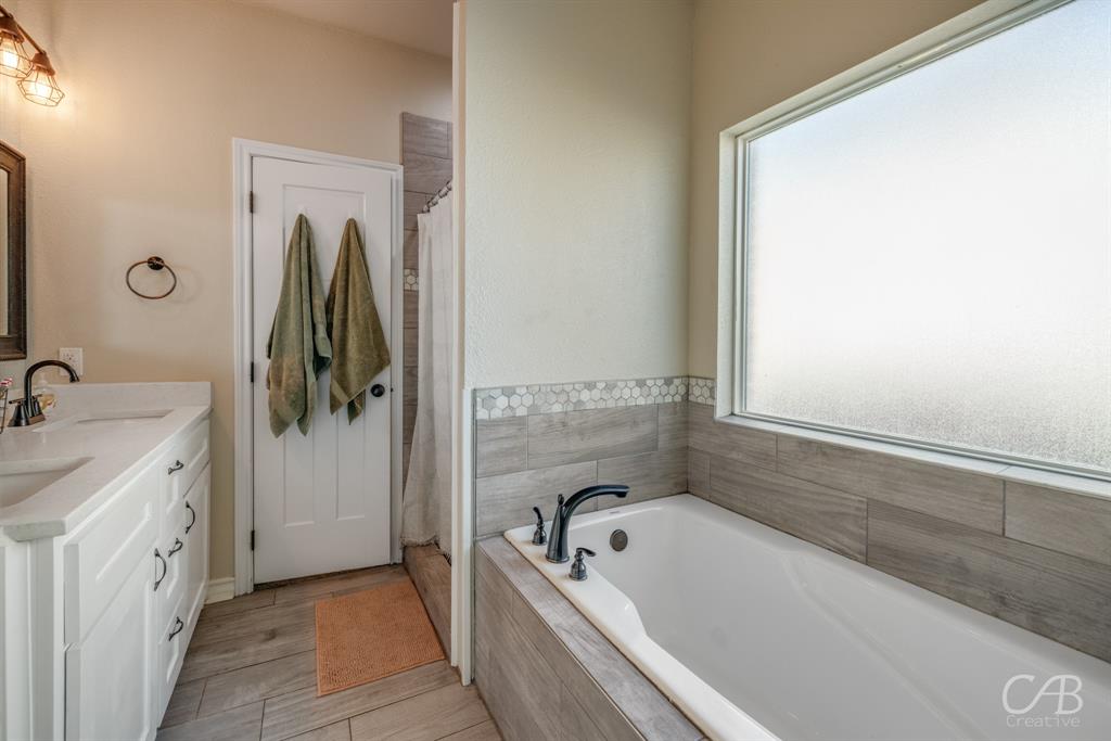 625 Jarrell Court Tuscola, TX 79562 - Photo 25 of 32 a bathroom with a tub a sink and a window