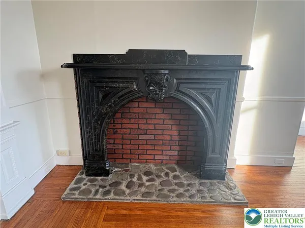an empty room with wooden floor fireplace and windows