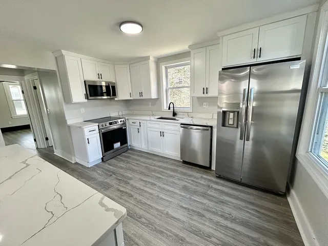 a kitchen with stainless steel appliances granite countertop a refrigerator a stove a sink and a microwave