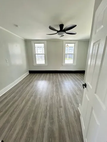 a view of a big room with wooden floor and windows