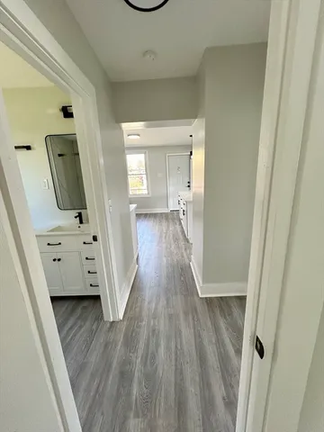 a view of a hallway to a livingroom with wooden floor and furniture