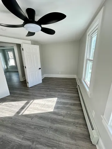 a view of an empty room with wooden floor and window