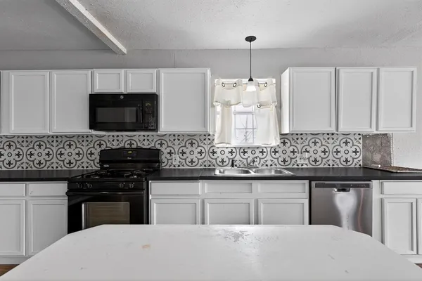 a kitchen with stainless steel appliances granite countertop a stove top oven a sink dishwasher and a microwave oven with wooden floor