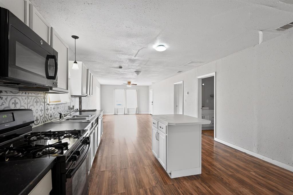 205 South Mable Street Ferris, TX 75125 - Photo 14 of 31 a kitchen with stainless steel appliances granite countertop a stove top oven a sink dishwasher and a microwave oven with wooden floor