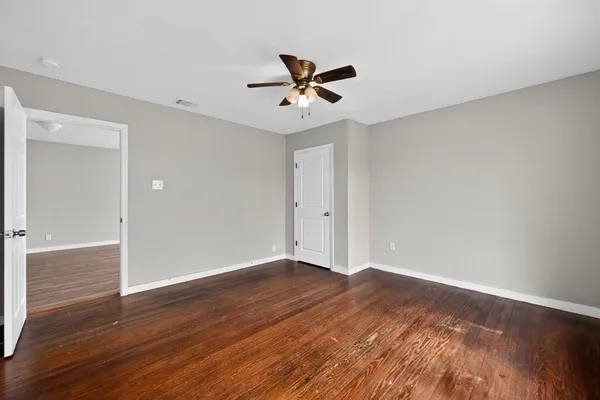 a view of empty room with wooden floor and fan