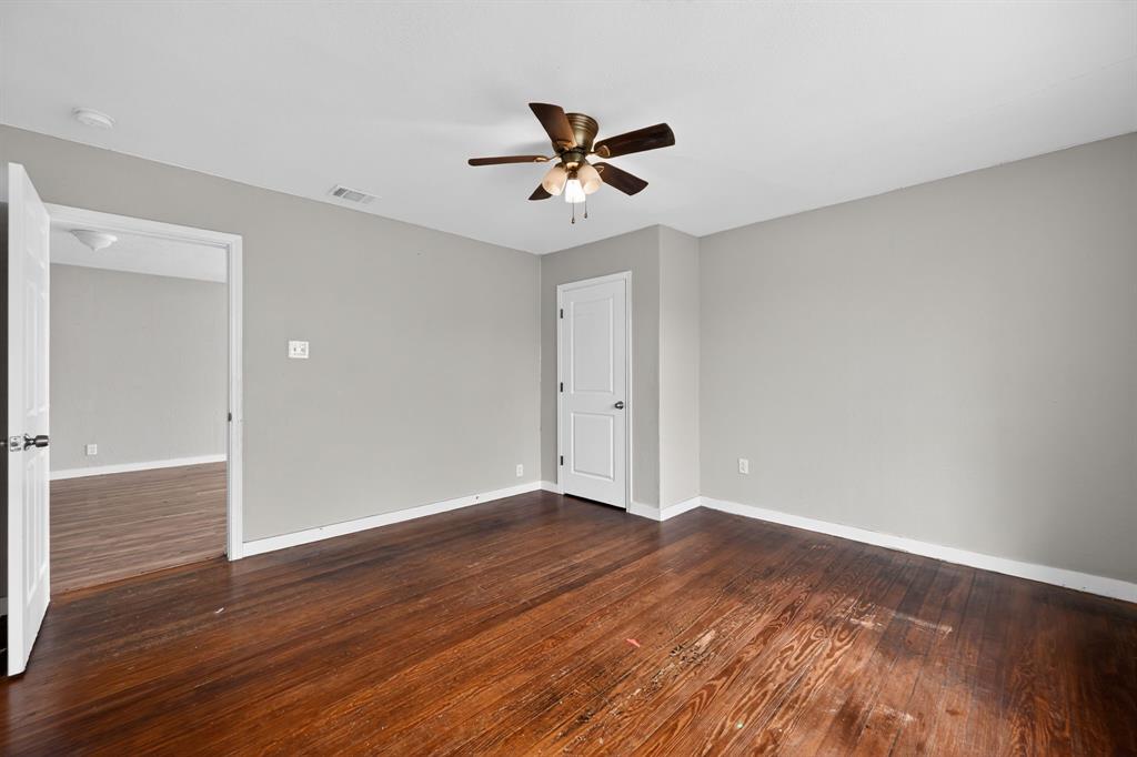 205 South Mable Street Ferris, TX 75125 - Photo 7 of 31 an empty room with wooden floor a ceiling fan and windows