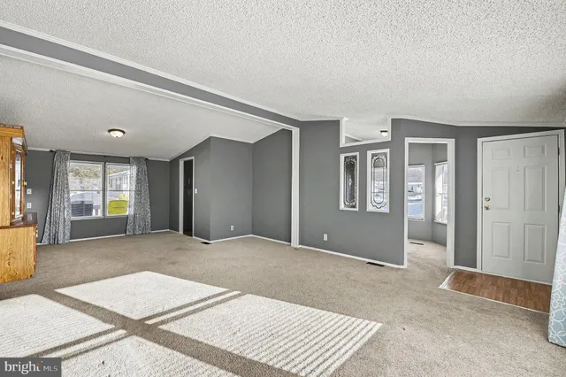 a view of an empty room with window and a kitchen