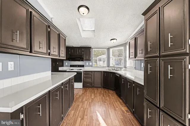 a kitchen with stainless steel appliances granite countertop a refrigerator a sink dishwasher a stove and a microwave oven with cabinets