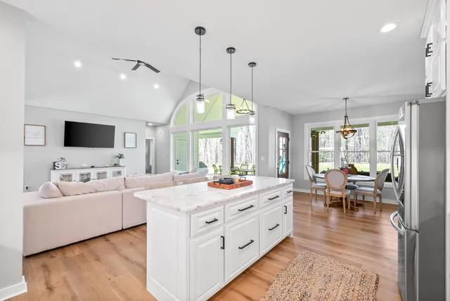 a kitchen with stainless steel appliances kitchen island granite countertop a sink a stove a refrigerator and chairs