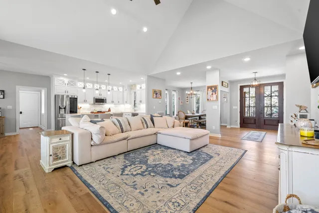 a large white kitchen with a stove a sink dishwasher and a refrigerator with wooden floor