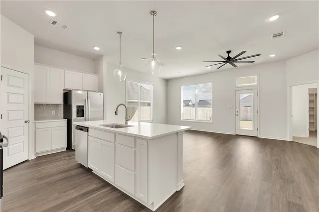 a kitchen with stainless steel appliances granite countertop a sink a stove and a refrigerator