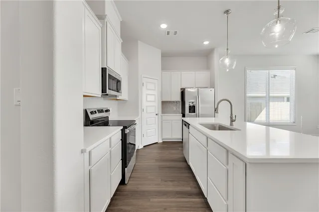 a kitchen with white cabinets sink and stainless steel appliances