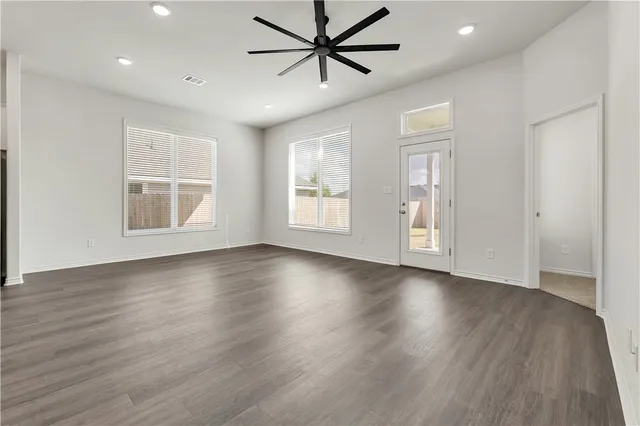 a view of an empty room with window and wooden floor