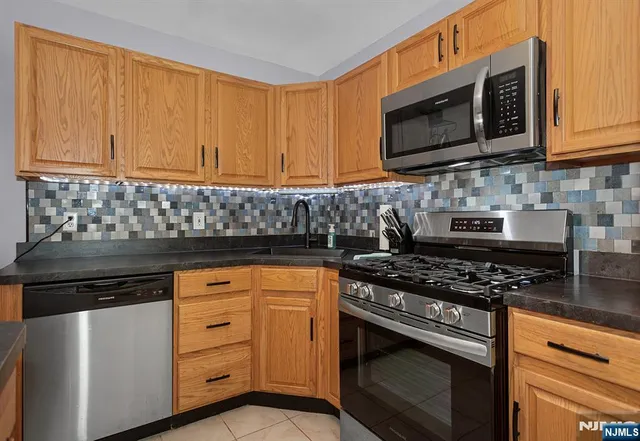 a kitchen with stainless steel appliances granite countertop white cabinets and black stove top oven with granite countertops