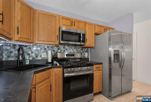 a kitchen with stainless steel appliances granite countertop a stove a refrigerator and a microwave