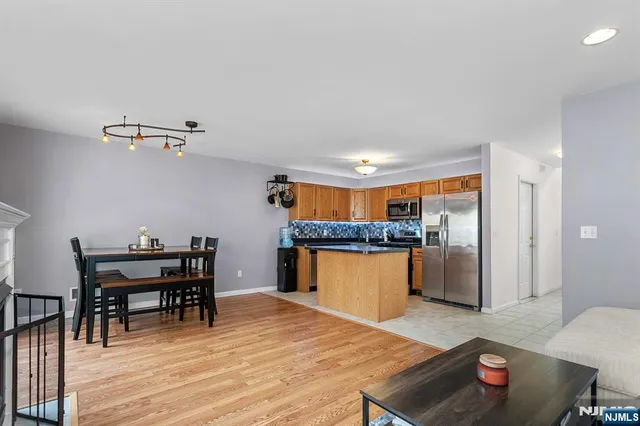 a kitchen with stainless steel appliances granite countertop a sink dishwasher and a dining table with wooden floor