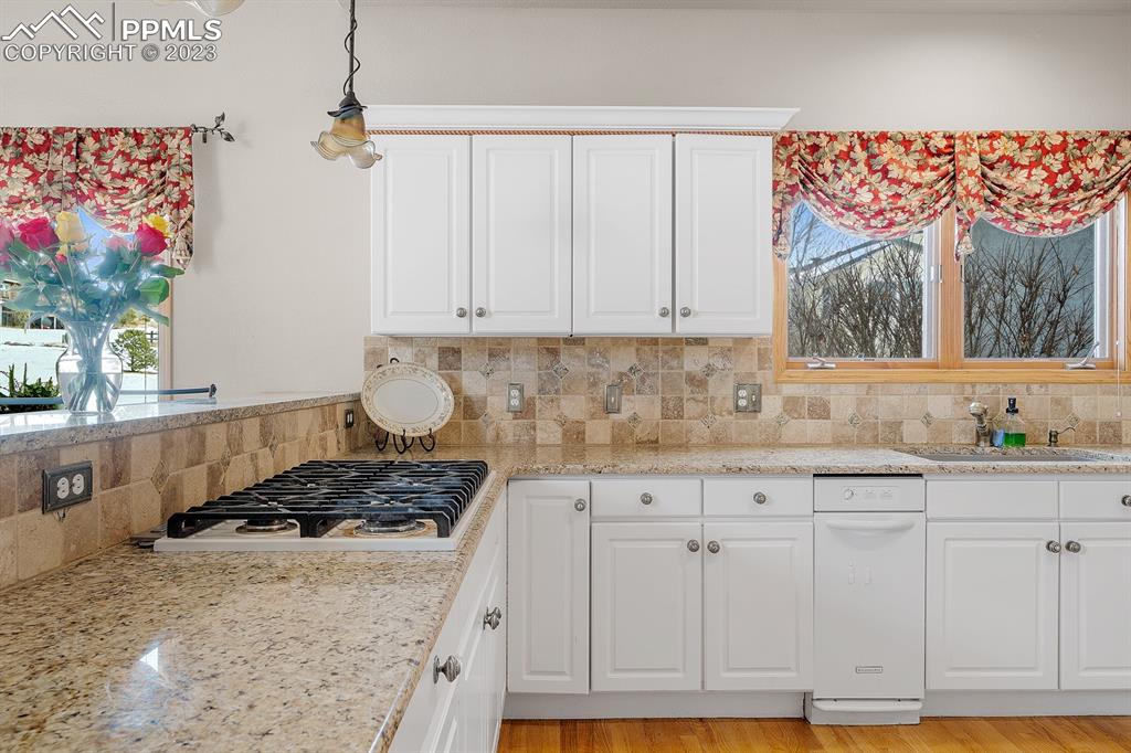 750 Bowstring Road Monument, CO 80132 - Photo 12 of 34 a kitchen with granite countertop a stove a sink cabinetry and chandelier