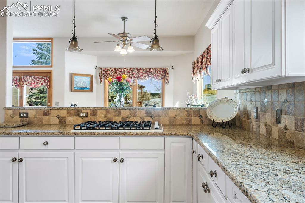 750 Bowstring Road Monument, CO 80132 - Photo 13 of 34 a kitchen with kitchen island granite countertop a sink cabinets and window