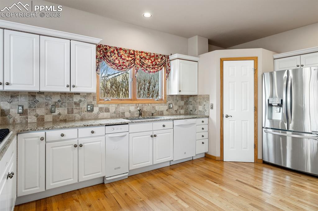 750 Bowstring Road Monument, CO 80132 - Photo 4 of 34 a kitchen with granite countertop white cabinets and refrigerator
