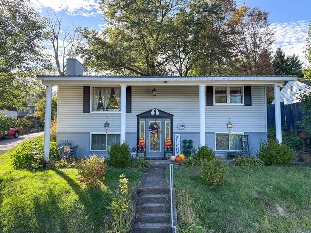 a front view of a house with a yard and trees