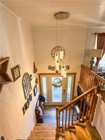 a view of a livingroom with furniture stairs wooden floor and windows