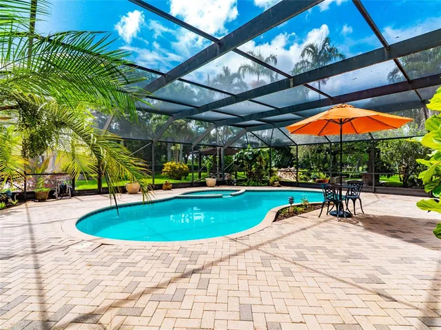 a view of pool with a table and chairs under an umbrella
