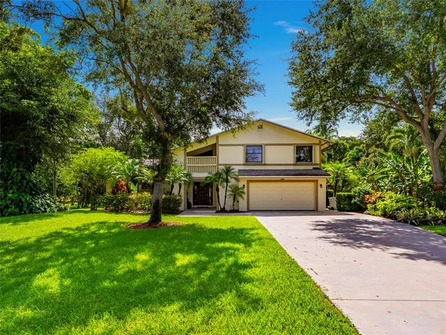 a view of a house with a big yard and large trees
