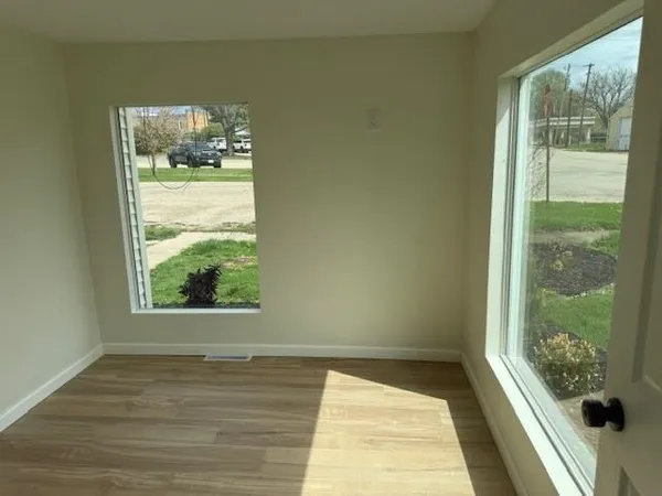 a view of empty room with wooden floor and fan