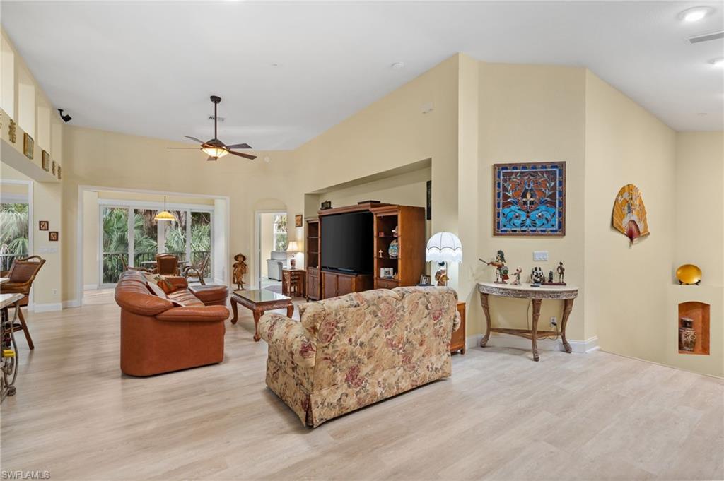 1665 Winding Oaks Way, Unit 202 Naples, FL 34109 - Photo 7 of 34 Living area with light wood-style flooring, a high ceiling, ceiling fan, and arched walkways