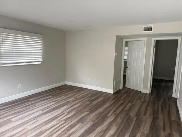 a view of an empty room with wooden floor and a window