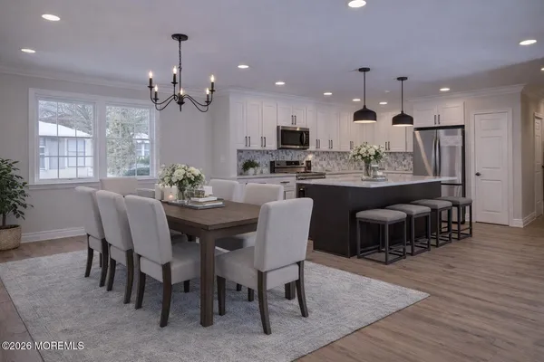 a dining room with stainless steel appliances kitchen island granite countertop a dining table chairs and wooden floor