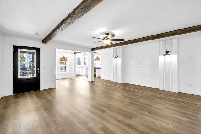 a view of an empty room with window and wooden floor