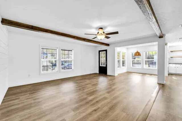 a view of an empty room with a window and wooden floor