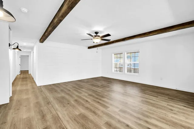 a view of empty room with wooden floor and fan